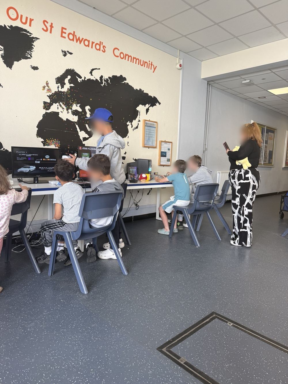 Children playing on a row of Pixcade gaming stations set up in a school hall
