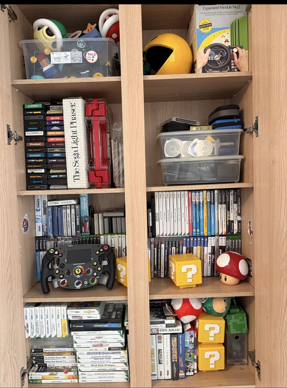 Shelves of retro games and accessories including Atari cartridges, a Sega Light Phaser, Pac-Man and Mario figures